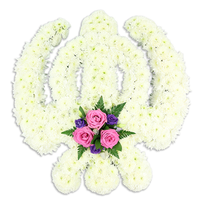 A serene Sikh Khanda floral tribute is shown in flawless detail, subtly lit against a bright white background that highlights its sculptural quality. The sacred symbol is built entirely from small white chrysanthemums, each head set shoulder to shoulder so that the arrangement feels dense and substantial, yet soft to the touch. The central double-edged sword stands tall, flanked by the encircling chakkar and the gracefully curved kirpans, all perfectly balanced and instantly recognisable to anyone familiar with Sikh iconography. The flowers' creamy white shade and feathery petals bring a gentle, contemplative mood, much like the quiet stretch of path along Deptford Park on an overcast afternoon. Tucked into the base of the Khanda, where the swords intersect, is a compact cluster of accent flowers that introduces a thoughtful contrast. Three generous pink roses, at that ideal point between bud and full openness, create a soft focal point, their layered petals reminiscent of folded silk. Around them nestle deep purple flowers, possibly lisianthus or freesias, intertwined with finely cut dark green fern fronds and a few supportive leaves that add depth and texture. This touch of colour at the heart of the design lends a sense of personal affection and remembrance, as though representing the loved one held within the embrace of faith. The white background and delicate shadow beneath the arrangement give it a calm, almost gallery-like setting, as if it has just been prepared in a Deptford Florist workshop off Evelyn Street and is ready to be carried respectfully to a nearby gurdwara or funeral home. The tribute conveys honour, devotion, and enduring connection, ideal for Sikh memorials and farewell ceremonies throughout Deptford and the surrounding neighbourhoods.