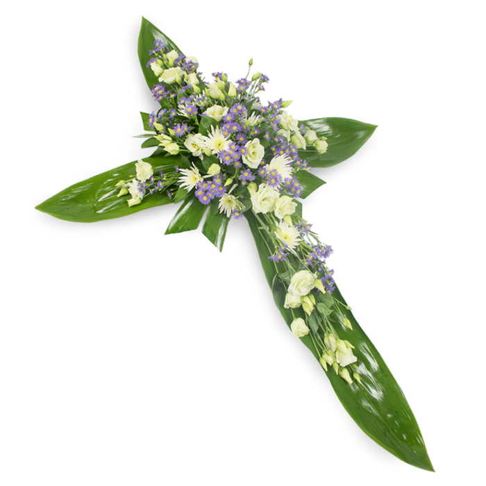 Photographed from a modest overhead angle on a plain white field, this floral cross combines sculptural foliage with a soft, tranquil floral heart. Large, glossy green leaves-resembling Ti or similarly broad tropical varieties-are carefully overlapped to define the cross's arms and central spine, their smooth surfaces and prominent veins giving the piece a sense of solidity and shelter. Resting at the centre and fanning gently along each arm are clusters of creamy-white lisianthus whose layered, ruffled petals speak of purity and gentle mourning; small, white chrysanthemum-style blooms punctuate the mass with bright, rounded texture; and fine sprays of pale lavender limonium or asters knit through the design, offering a cooling contrast that deepens the composition. Woven throughout are delicate green fillers that lighten transitions between flowers and leaf, making the whole feel organic and thoughtfully composed. The lighting bathes the arrangement evenly, revealing a serene interplay of shine and softness that feels almost meditative, as though the cross were resting quietly in a chapel near Deptford Park or laid at a service on Deptford Bridge. This piece is clearly intended as a sympathy tribute-a dignified emblem of faith and remembrance that balances sympathy with an understated hope for peace and the permanence of memory.
